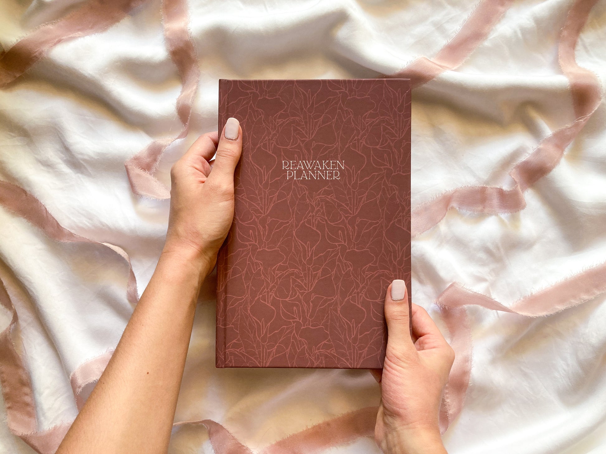 Image of Reawaken Planner cover. Maroon background with calla lily pattern texture.